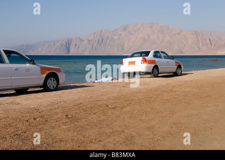 Local taxi driver nido di sonno per le loro auto parcheggiate sulla sabbia di sputo di Laguna Bay nel Sinai resort di Dahab in Egitto Foto Stock