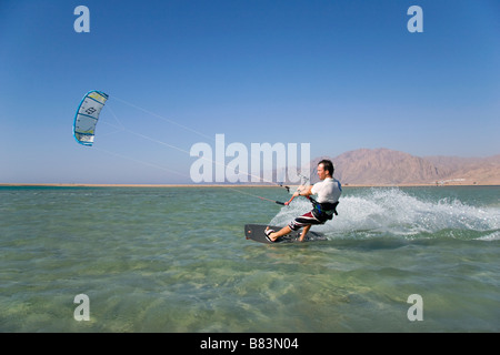 Un kitesurfer attraversa il turchese acqua piatta laguna (QURA BAY) all'interno della sabbia sputa nel Sinai resort di Dahab in Egitto Foto Stock