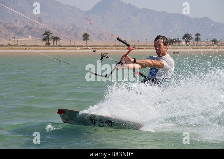 Un kitesurfer attraversa il turchese acqua piatta laguna (QURA BAY) all'interno della sabbia sputa nel Sinai resort di Dahab in Egitto Foto Stock