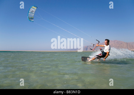 Un kitesurfer attraversa il turchese acqua piatta laguna (QURA BAY) all'interno della sabbia sputa nel Sinai resort di Dahab in Egitto Foto Stock