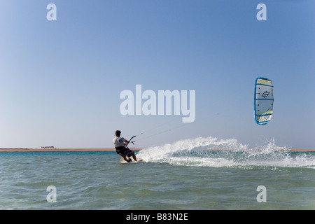 Un kitesurfer attraversa il turchese acqua piatta laguna (QURA BAY) all'interno della sabbia sputa nel Sinai resort di Dahab in Egitto Foto Stock