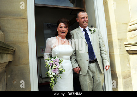 Coppia di novelli sposi a piedi al di fuori dell'ufficio del registro di sistema, North Yorkshire Modello rilasciato Foto Stock