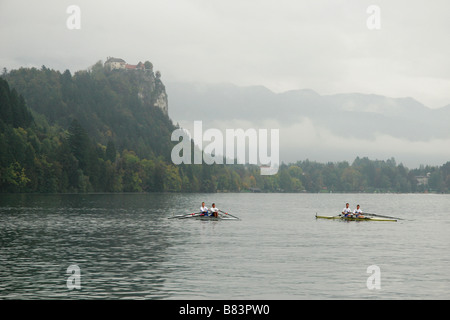 Coxless coppie ad una regata sul Lago di Bled con il castello di Bled arroccato sulla scogliera dietro, sulle Alpi Giulie, in Gorenjska, Slovenia Foto Stock