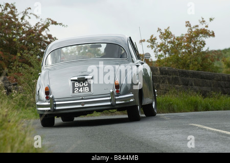 Jaguar Mk2 automobili la curva su una strada di campagna Foto Stock