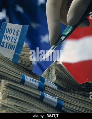 Taglio chirurgicamente una pila di 100 fatture a metà con una bandiera americana sfondo Foto Stock