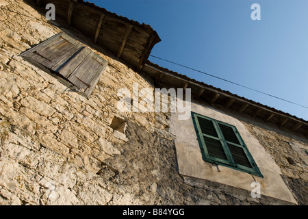 Casa di mattoni a parete con due finestre serrande di chiusura sopra il cielo nel villaggio di Omodhos, monti Troodos, Cipro del Sud Foto Stock