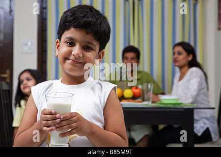 Un ragazzo sorridente e tenendo un bicchiere di latte Foto Stock