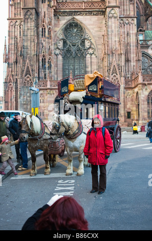 Donna asiatica che è fotografata davanti a cavallo omnibus, cattedrale di Strasburgo, Alsazia, Francia Foto Stock