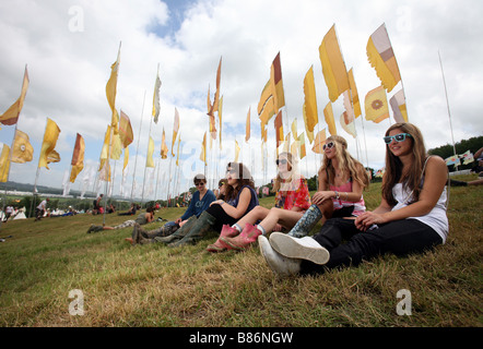 Un gruppo di ragazze godetevi il sole sat tra bandiere al Glastonbury festival in Pilton, Somerset nel Regno Unito. Foto Stock
