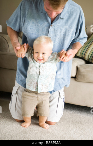 Padre aiutando il figlio a piedi Foto Stock