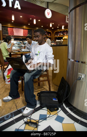 I passeggeri della compagnia aerea funziona su computer lap top nella sala partenze dell'aeroporto internazionale di Bahrain. (45) Foto Stock