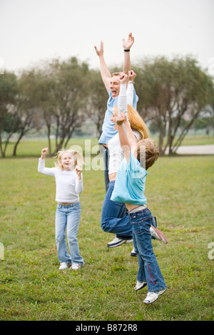 Famiglia salta con le mani in aria Foto Stock