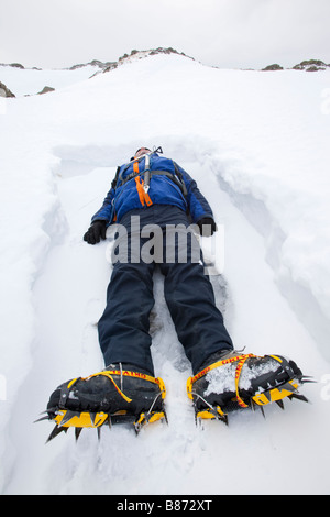 Un uomo disteso nella neve su Crinkle Crags nel distretto del lago REGNO UNITO Foto Stock