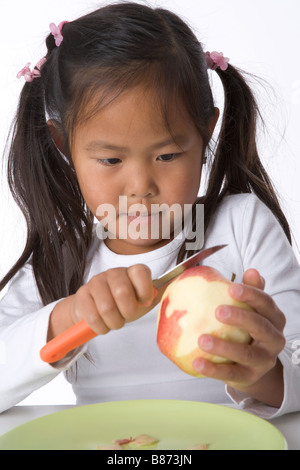 Bambina bucce è una mela con un coltello Foto Stock