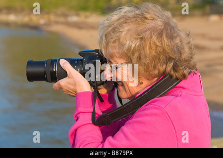 Donna di scattare una foto con la fotocamera digitale Canon, Inghilterra Foto Stock