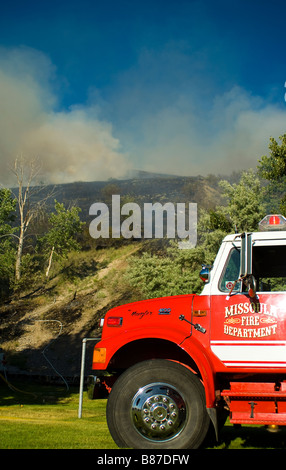 Wild fire infuriano su una montagna con un camion dei pompieri in primo piano. Foto Stock