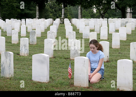 Una giovane ragazza in un cimitero militare in onore di un soldato caduto Foto Stock