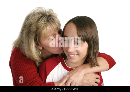 Una madre che dà un bacio sulla guancia al suo figlio adolescente isolato Foto Stock