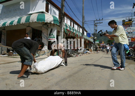 Il personale dei servizi di emergenza il prelevamento di un corpo fuori strada a Patong Beach sull'Isola di Phuket, Thailandia, dopo il 26 dicembre 2004 tsunami. Foto Stock