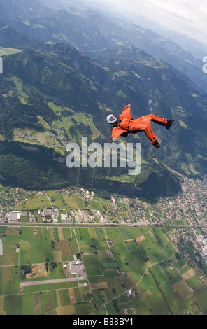 Paracadutista è volare sulla schiena con un wingsuit su un paesaggio spettacolare. Il subacqueo è il percorso lungo il crinale. Foto Stock