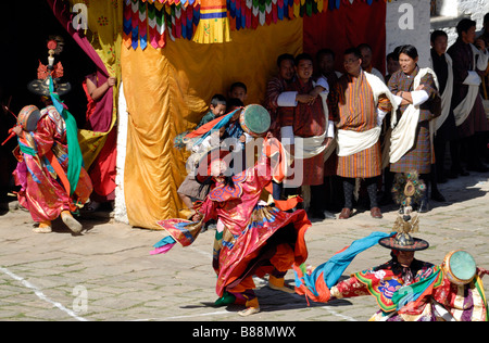 Black Hat ballerini in splendide vesti di seta ballerini twist e spin di fronte ad una platea in Bhutan vestito nazionale Foto Stock