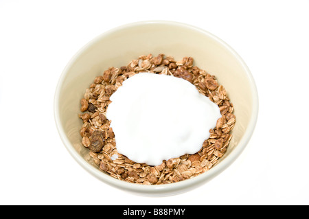 Cereali Granola di fiocchi d'avena con frutta secca e noci e rabboccato con lo yogurt in una ciotola su sfondo bianco Foto Stock