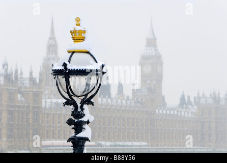 Scena innevata a Londra, con una lampada da strada ornata che si distingue contro la neve che cade, con il Big Ben e parte del Parlamento. Foto Stock