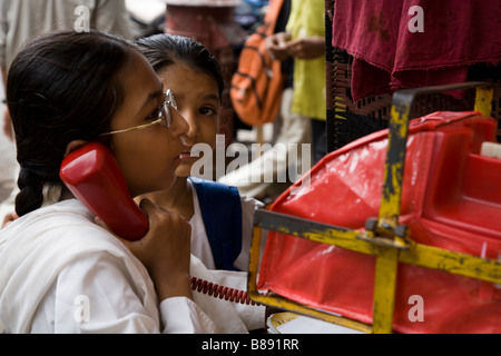 Due Indian School ragazze utilizzando un telefono pubblico, in Mumbai. Foto Stock