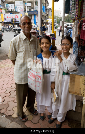 Indiano uomo indù accompagnamento due ragazze della scuola. Mumbai, India. Foto Stock