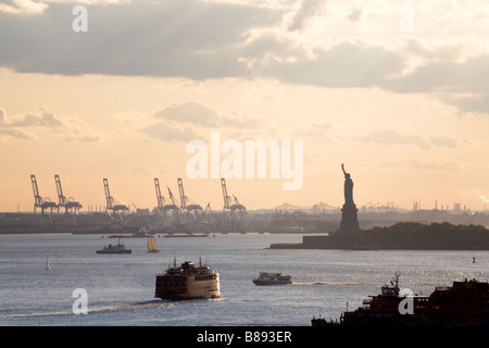 Una vista serale di molte barche che viaggiano nella Baia di Hudson e passando davanti alla statua della Libertà. Foto Stock