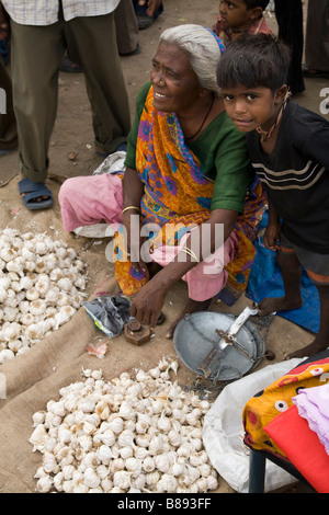 Donna venditore di aglio con il suo mercato di strada in stallo sul terreno. Hazira, Surat, Gujarat. India. Foto Stock