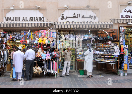 People & Dubai shopping Street scene piccoli negozi e negozi esposizione vendita di merci variegate per gli acquirenti Emirati Arabi Uniti Emirati Arabi Uniti Medio Oriente Foto Stock