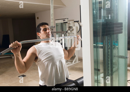 L'uomo facendo lat pulldown di esercizio in palestra Foto Stock