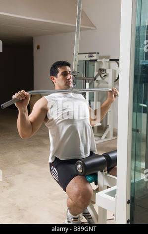 L'uomo facendo lat pulldown di esercizio in palestra Foto Stock