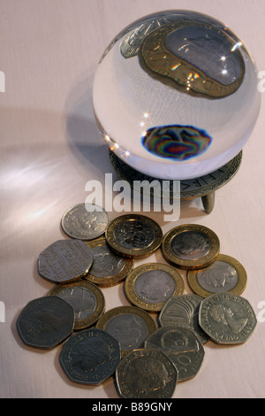 Una fotografia di una sfera di cristallo ingrandimento di una parte di un due pound coin circondato da altre monete di GBP in background. Foto Stock