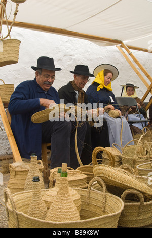 Gli artigiani in costume tradizionale cesti che fanno fuori di sparto presso la tradizionale fiera di artigianato, Santa Eulalia, Ibiza, Spagna Foto Stock