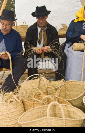 Gli artigiani in costume tradizionale cesti che fanno fuori di sparto presso la tradizionale fiera di artigianato, Santa Eulalia, Ibiza, Spagna Foto Stock