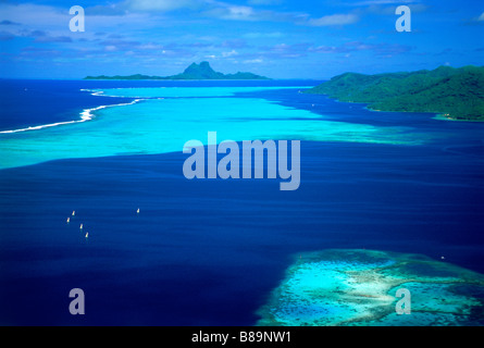 Barche a vela in laguna di Tahaa con isola di Bora Bora in distanza in Polinesia francese Foto Stock