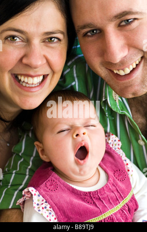 Ritratto verticale di un orgoglioso il padre e la madre con il loro neonato figlia sbadigli Foto Stock