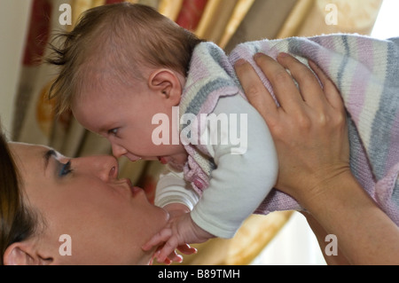 Ritratto orizzontale di una giovane madre sollevando la sua bimba in aria per darle un bacio Foto Stock
