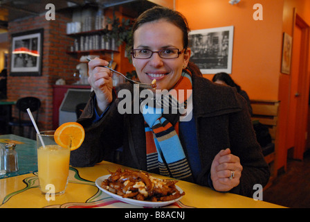 Donna di mangiare tradizionale poutine in La Banquise ristorante Quebec Montreal Canada Foto Stock