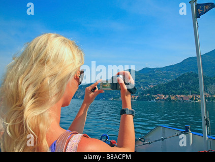 Giovane donna prendendo fotografia da un passeggero con una traversata in traghetto da Bellagio a Varenna sul lago di Como Foto Stock