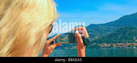 Giovane donna prendendo fotografia da un passeggero con una traversata in traghetto da Bellagio a Varenna sul lago di Como Foto Stock