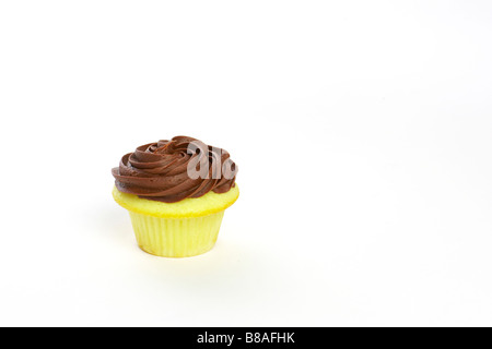 Un singolo cupcake alla vaniglia con glassa di cioccolato su uno sfondo bianco. Foto Stock