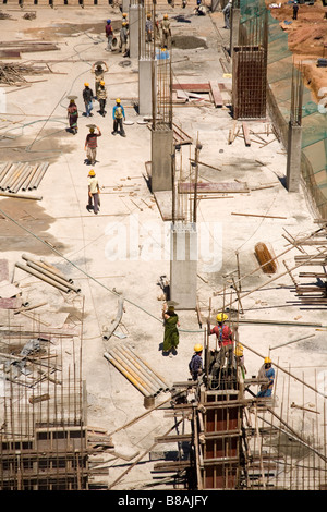 Gli uomini e le donne che lavorano insieme per versare cemento sul tondino in acciaio armature di un sito in costruzione a Bangalore in India. Foto Stock