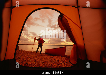 FV3309, Dave Reede; Man Standing Shore canoa, visto attraverso porta/n tenda, poco calcare /nLake, Manitoba Foto Stock