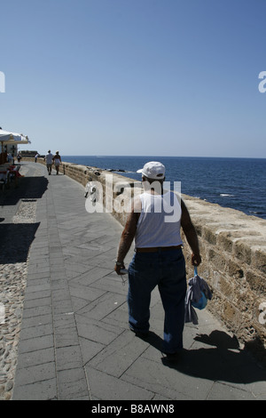 Il vecchio uomo che cammina lungo la parete del mare di Alghero Sardegna Italia Foto Stock