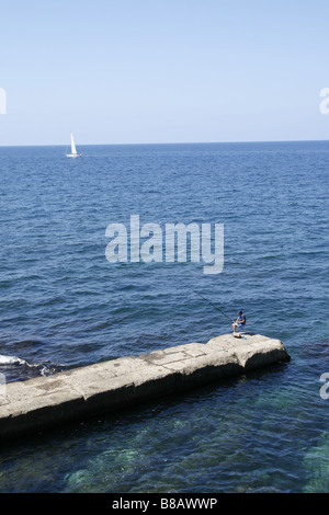 Uomo di pesca sul molo sul mare di Alghero, Sardegna, Italia Foto Stock