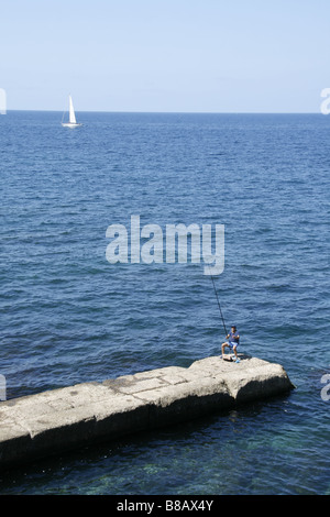 Uomo di pesca sul molo sul mare di Alghero, Sardegna, Italia Foto Stock