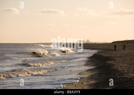 Walkers sul Southwold Beach in inverno sera sole pomeridiano con luce Sizewell centrale nucleare a distanza Foto Stock